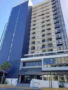 a tall blue building with a palm tree in front of it at Sun N Sand Resort in Myrtle Beach