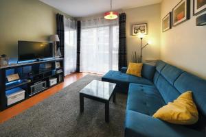 a living room with a blue couch and a tv at Apartament Baltic Park Plaża 1.1.1 in Świnoujście