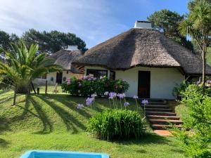 ein Haus mit Strohdach und Blumen in der Unterkunft CASA MARÍTIMA EN PORTEZUELO, MALDONADO, URUGUAY in Punta del Este