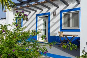 Casa azul y blanca con mesa y sillas en Change The World - Herdade Monte do Peral, en Montes Juntos