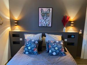 een slaapkamer met een bed met blauwe kussens en een schilderij bij Confort Home - Disneyland Paris à 10 minutes à pied- Marne la Vallée- Paris in Serris