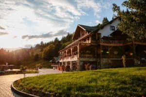 a large wooden house with people on the balcony at Conacul Baciu in Fundu Moldovei