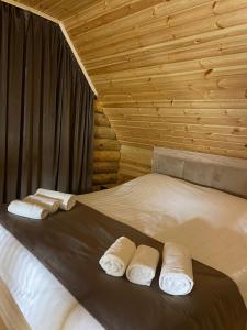 Una cama en una habitación de madera con toallas. en Riverside Eco Resort, en Debed