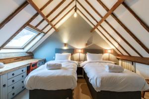 two beds in a attic room with a window at Otters Abode in Blockley