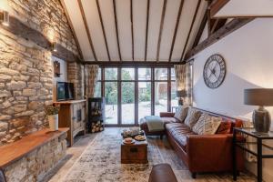 a living room with a couch and a stone wall at Otters Abode in Blockley