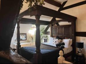 a bedroom with a bed with a wooden canopy at Blenheim House Hotel in Etwall