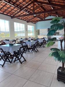 uma sala de jantar com mesas e cadeiras e uma palmeira em Hotel Trevo Caruaru em Caruaru