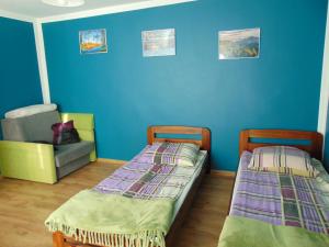 two beds and a chair in a room with blue walls at POD RÓŻĄ in Kasina Wielka