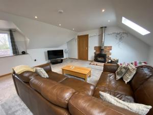 ein Wohnzimmer mit einem braunen Ledersofa und einem Kamin in der Unterkunft New Bury Cottage near Goodwood in Chichester