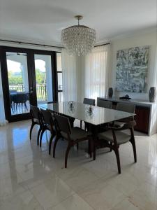 a dining room with a table and chairs and a chandelier at The Country Club Residences at Grand Reserve in Rio Grande