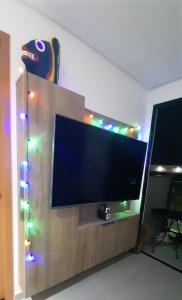 a flat screen tv on a stand with christmas lights at Flat La Ursa da Praia in Porto De Galinhas