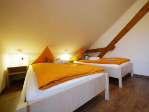 2 camas con sábanas de color naranja en una habitación en Ferienwohnung 5 en Ochsenhausen
