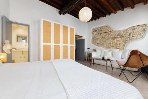 a bedroom with a large white bed and a stone wall at Venghera Naousa Apartment in the heart of Naousa in Naousa +51 photos