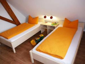 2 letti con lenzuola arancioni in una piccola stanza di Ferienwohnung 3 a Ochsenhausen