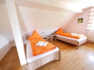 2 camas con almohadas de color naranja en una habitación en Ferienwohnung 11 en Ochsenhausen