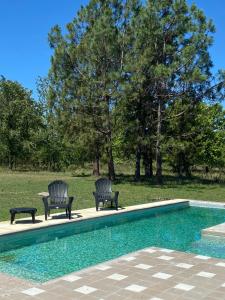 2 sillas sentadas junto a una piscina en Los Sauces hospedaje rural en Capilla del Señor