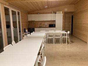 a large kitchen with white tables and white chairs at COMPLEX TURISTIC Gradina de corzi si Aventura Eselnita in Eşelniţa