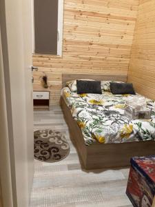 1 dormitorio con 1 cama y pared de madera en COMPLEX TURISTIC AVENTURA CAMP, en Eşelniţa