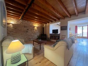 ein Wohnzimmer mit weißen Möbeln und einer Ziegelwand in der Unterkunft Les Cerisiers Gîtes in Lezay