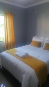 a bedroom with two beds with white sheets and yellow curtains at Goshen Place in East London