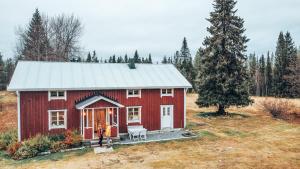 una casa roja en un campo con un árbol en Taiga Forest Lodge en Gällivare