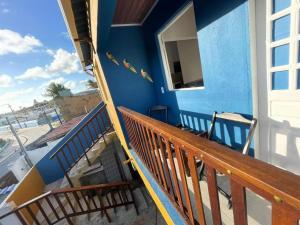 a blue house with a wooden railing on a balcony at Casa na Orla - Praia de Gaibu! in Cabo de Santo Agostinho