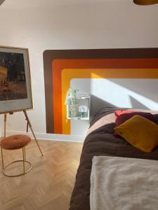 um quarto com uma cama, um quadro e uma cadeira em Agréable chambre d'hôte 70s au cœur de l'Alsace em Bouxwiller