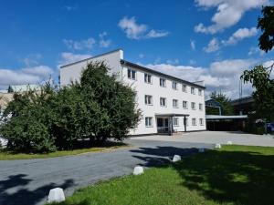 a white building with a tree in front of it at Penzion Barborka in Olomouc