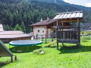 - une aire de jeux avec trampoline dans un champ avec une maison dans l'établissement Beim Gruber, à Melago