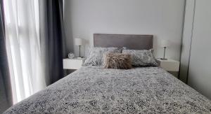 a bed with a black and white comforter and pillows at NidoAparte II. Nuevo departamento en Lujan Centro in Luján