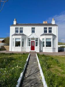 una gran casa blanca con puerta roja en Bixter House - a spacious self-catering property 