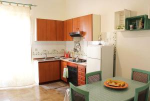 a kitchen with a table and a white refrigerator at Sicilia Nica - appartamento privato a Cinisi (PA) in Cinisi