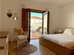 a bedroom with a bed and a chair and a balcony at PIER HOUSES by Nature Bliss in Vila Nova de Milfontes