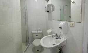 a white bathroom with a toilet and a sink at Hotel Travelers Sport in Cali