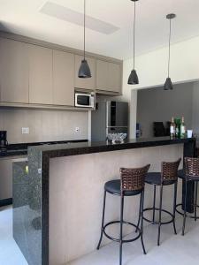 uma cozinha com três bancos de bar num balcão em Beach House Olímpia - Casa Temporada em Olímpia mais 25 fotografias