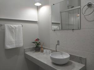 a white bathroom with a sink and a mirror at Aconchego e tranquilidade junto ao H. Mãe de Deus in Porto Alegre