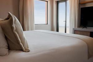 a bedroom with a white bed with a large window at Cottage Carrasco in Montevideo