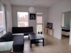 a living room with a black couch and a table at Helsinki Private-Yksityinen-Частный Room in Shared Apartment into Airport-BusTrain Station-University in Helsinki