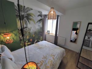 een slaapkamer met een hemelbed met een palmmuurschildering bij Appartement T2 "JUNGLE" Centre Ville de VITRÉ au calme coté cour in Vitré