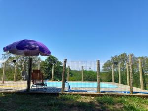 an umbrella and a chair next to a swimming pool at Suítes no Refúgio da Mata Atlântica - Sobrado Centenário in Torres