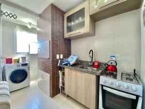 a small kitchen with a stove and a washing machine at Pé na areia em Capão in Capão da Canoa