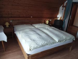 duże łóżko w pokoju z drewnianymi ścianami w obiekcie Haus Ferner-Lerchner w mieście Mariapfarr