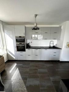 cocina con armarios blancos y suelo de baldosa en Superbe appartement proche de Strasbourg, en Bischheim