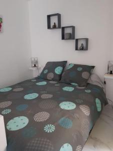 sypialnia z łóżkiem z zieloną i niebieską narzutą w obiekcie logement indépendant avec terrasse "Les Mésanges" w mieście Juvignac