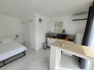 Kleines weißes Zimmer mit einem Bett und einem Schreibtisch. in der Unterkunft Studio "Les Mésanges" in Juvignac
