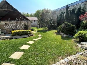 un jardín con un camino de piedra en el césped en Relais de Poste des Templiers en Jouaignes