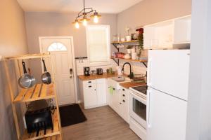Cozy Home in Downtown Winnipeg في وينيبيغ: مطبخ مع ادوات بيضاء وثلاجة بيضاء