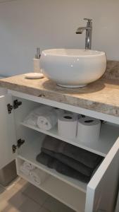 Apto Centro Gramado في غرامادو: حمام مع حوض ومناشف على رف