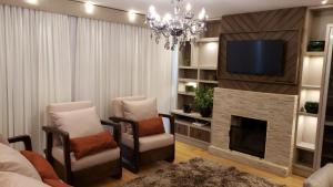 Apto Centro Gramado في غرامادو: غرفة معيشة مع مدفأة وتلفزيون