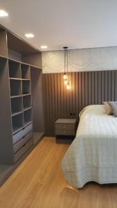 Apto Centro Gramado في غرامادو: غرفة نوم بسرير أبيض وأرضية خشبية